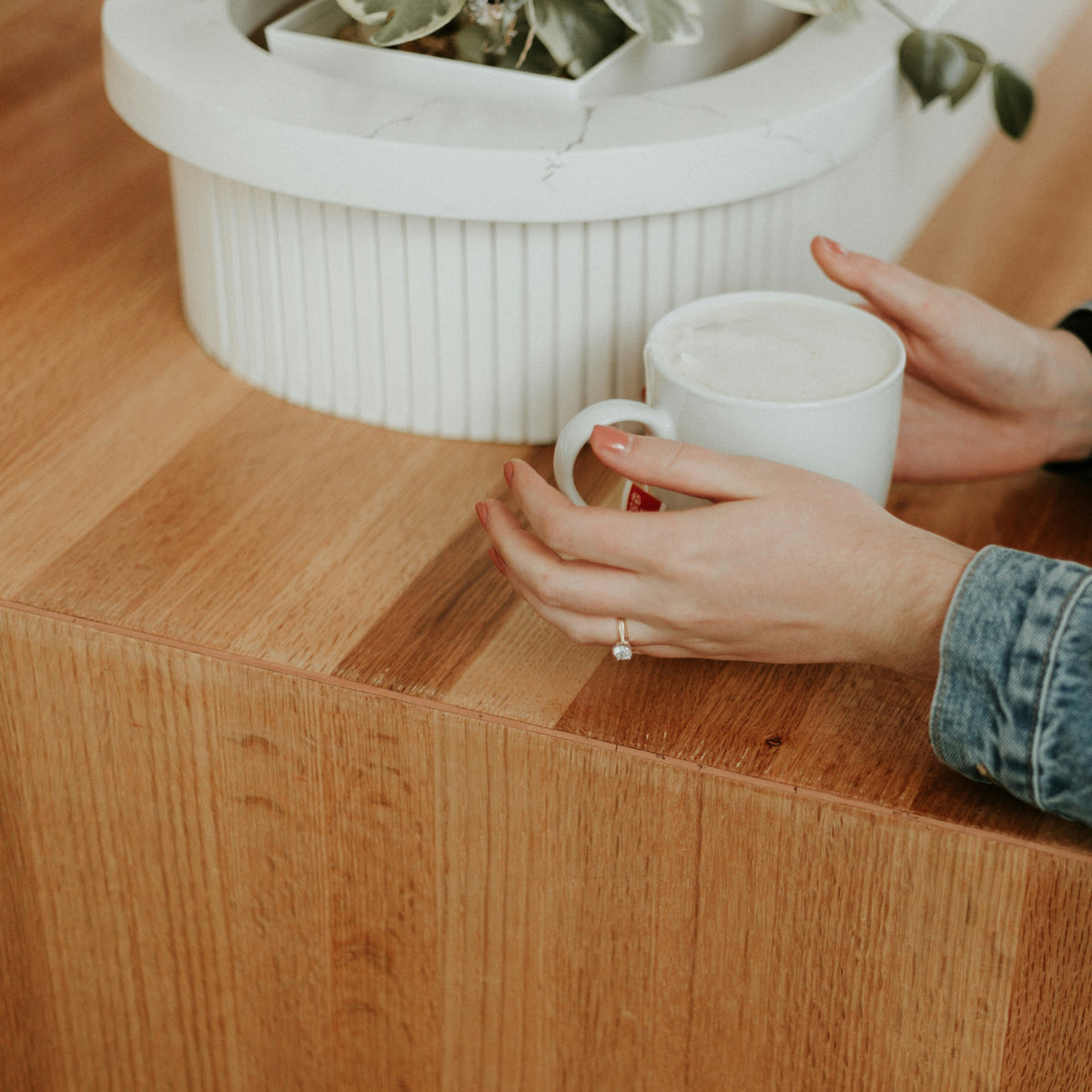 Person holding a white mug beside a timber benchtop