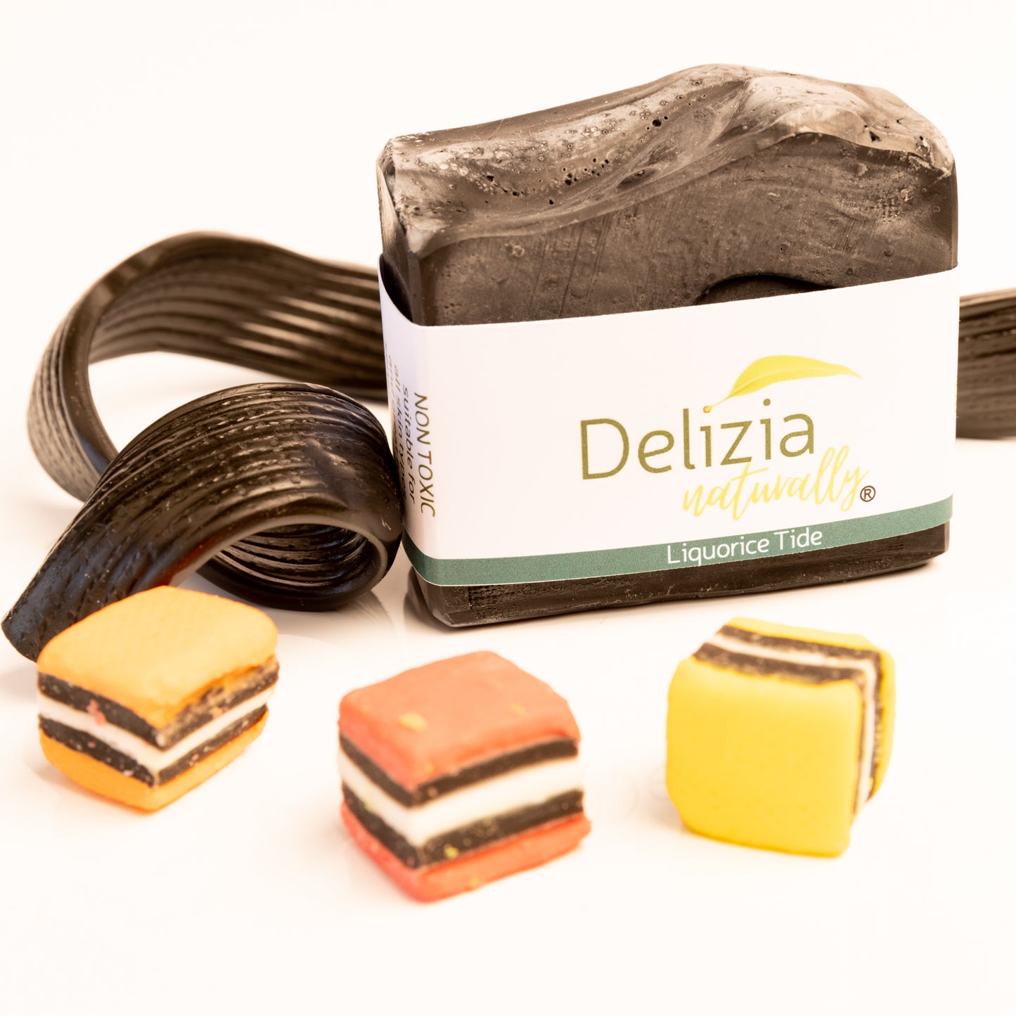 . Liquorice_Tide - coconut and aniseed soap - Delizia Naturally. Delizia Liquorice Tide product with licorice candy and small candy bars on a white background