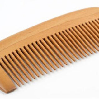 A light brown wooden comb with a smooth finish, photographed on a clean white background.