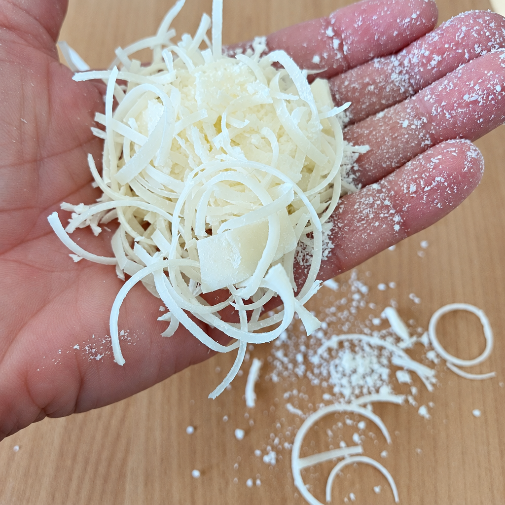 Hand holding Delizia Naturally pure beef tallow soap flakes over a wooden surface