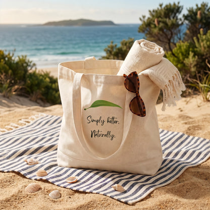 Delizia Naturally natural cotton canvas tote bag at the beach filled with towel and sunglasses