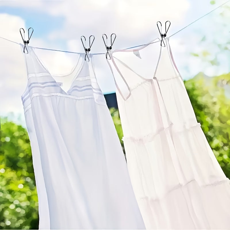 Two white sleeveless babydoll-style dresses hanging by stainless steel pegs  from a clothesline outdoors with green foliage and a blue sky in the background.